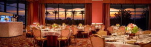 Luxury Las Vegas event venue at Wynn set for a private dinner with panoramic sunset views, floral centerpieces, and elegant table settings.
